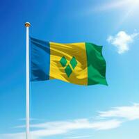 Waving flag of Saint Vincent on flagpole with sky background. photo