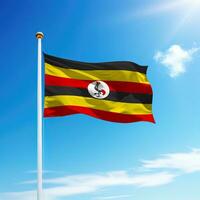Waving flag of Uganda on flagpole with sky background. photo