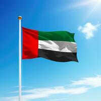 Waving flag of United Arab Emirates on flagpole with sky background. photo