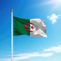 Waving flag of Algeria on flagpole with sky background. photo