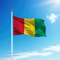 Waving flag of Guinea on flagpole with sky background. photo