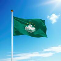 Waving flag of Macao on flagpole with sky background. photo