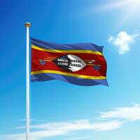 Waving flag of Eswatini on flagpole with sky background. photo