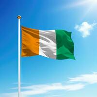 Waving flag of Ivory Coast on flagpole with sky background. photo