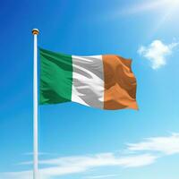 Waving flag of Ireland on flagpole with sky background. photo