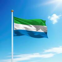 Waving flag of Sierra Leone on flagpole with sky background. photo