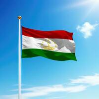 Waving flag of Tajikistan on flagpole with sky background. photo