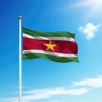 Waving flag of Suriname on flagpole with sky background. photo
