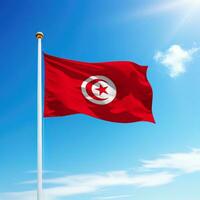 Waving flag of Tunisia on flagpole with sky background. photo