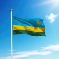 Waving flag of Rwanda on flagpole with sky background. photo