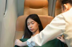 Female passenger sleeping covered with blanket by good care of air hostess during flight. photo