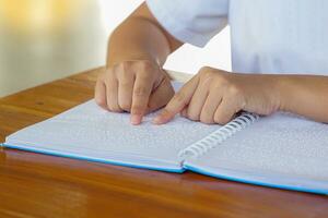 visualmente dañado persona lee con su dedos un libro escrito en braille eso es escrito para esos quien son visualmente dañado o ciego. eso es un especial código generado desde 6 6 puntos en el caja. foto