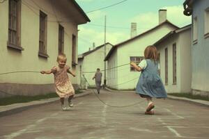 Children jumping rope and playing hopscotch photo