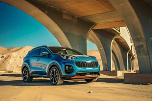 a blue kia sportage is parked under a bridge in the photo