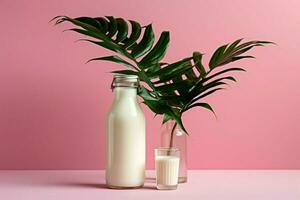 a bottle of milk next to a plant on a pink background photo