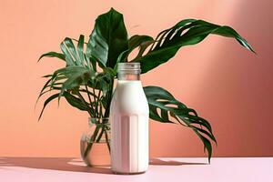 a bottle of milk next to a plant on a pink background photo