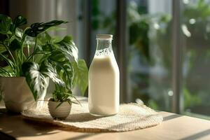a bottle of milk sits on a table next to a plant photo