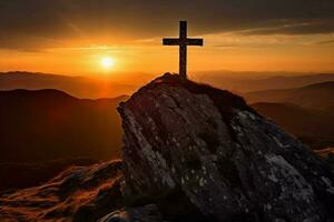 cross on a mountain with the sun setting behind it photo