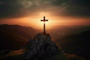 cross on a mountain with the sun setting behind it photo