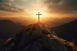 cross on a mountain with the sun setting behind it photo