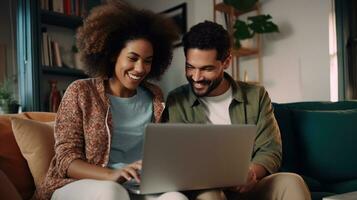 Happy Multiracial Couple is seated on their sofa, browsing the internet on their laptop. photo