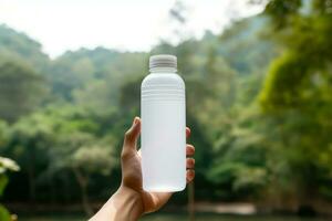 Hands holding a white bottle of whey protein on nature background photo