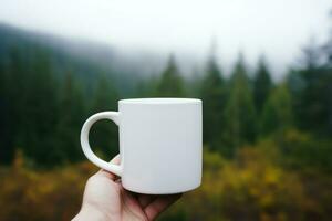 Hand holding a white mug on the background of a mountain landscape. photo