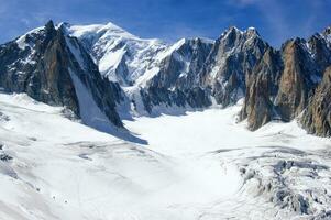 two people are hiking up a mountain with snow covered mountains photo