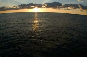 a boat is sailing across the ocean at sunset photo