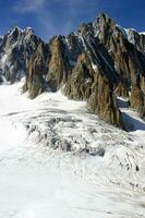 two people are hiking up a mountain with snow covered mountains photo