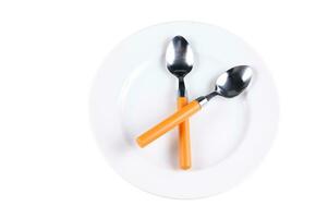 two spoons with orange handles on a white plate photo