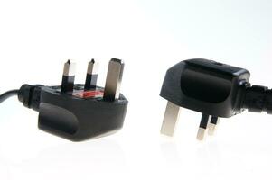 two black plugs with one plugged into the wall photo