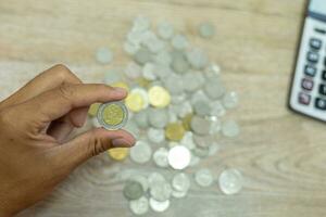 recortado ver de del hombre de negocios manos haciendo cálculos y poniendo monedas en cerdo banco a salvar dinero, Finanzas concepto foto