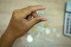 Cropped view of businessman's hands doing calculations and putting coins in pig bank to save money, finance concept photo