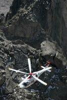 a helicopter is flying over a rocky mountain photo