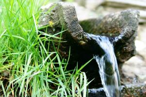 a small waterfall flowing out of a rock photo