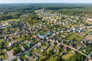 panoramic aerial view of small provincial town or big eco village with wooden houses, gravel road, gardens and orchards photo