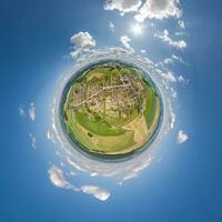 tiny planet in sky with clouds overlooking old town, urban development, historic buildings and crossroads. Transformation of spherical 360 panorama in abstract aerial view. photo