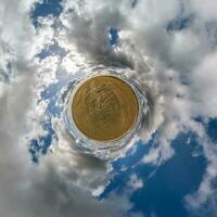 green tiny planet in blue sky with beautiful clouds with transformation of spherical panorama 360 degrees. Curvature of space. photo