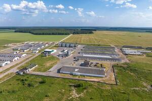 aerial panoramic view over livestock farm and agro-industrial complex with silos and rows of barns, pigsties, chicken coops photo