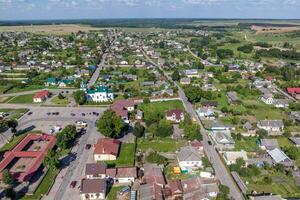 panoramic aerial view of eco village with wooden houses, gravel road, gardens and orchards photo