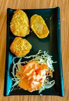 Japanese chicken nuggets with salad served on a black plate photo