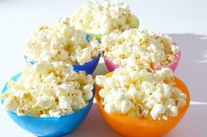 four colorful bowls of popcorn on a white surface photo