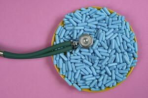 plate with medicine capsules and stethoscope photo