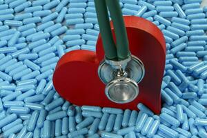 heart shape and medicine capsules representing heart problems and treatment photo