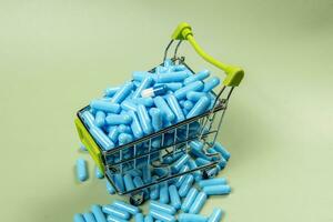 blue medicine capsule in miniature shopping cart photo