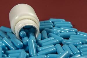 blue medicine capsules and white bottle photo