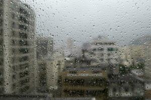 window glass with raindrops showing blurred city in the background photo