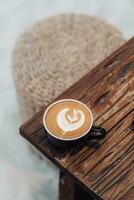 cerca arriba café taza con corazón forma latté Arte en madera lengüeta foto