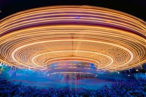 un noche escena de hilado alegre Vamos redondo carrusel en disneylandia bajo obturador velocidad. borroso foto